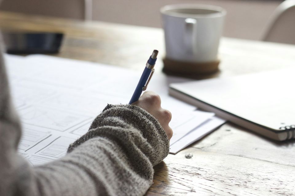 A hand working through application documents at a desk