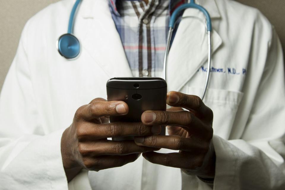 Close-up of a doctor in a white coat checking correspondence on a phone