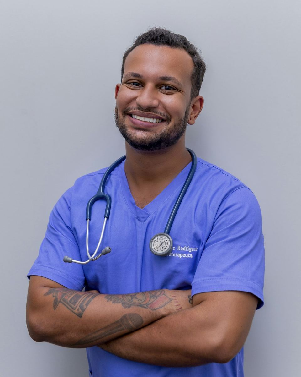 A doctor in scrubs smiling in a clinic corridor
