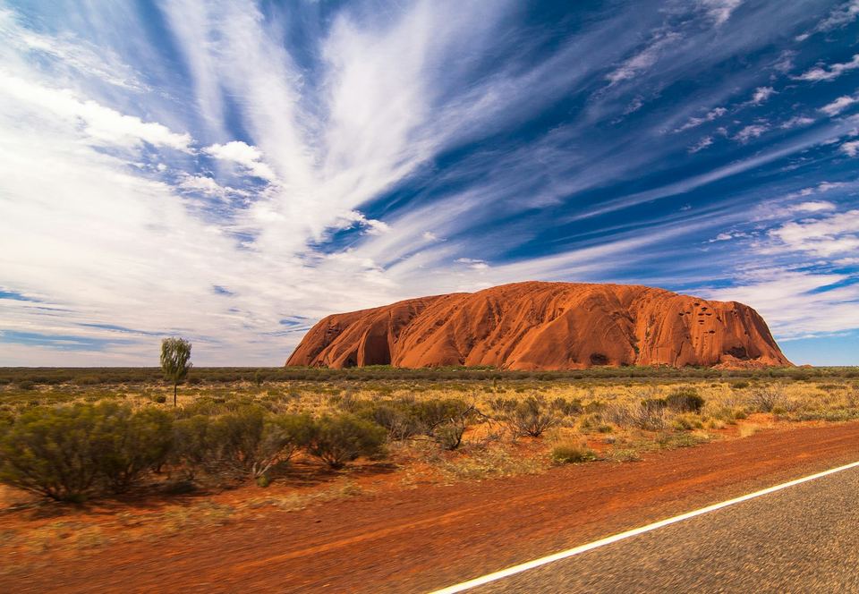 A sealed road running through red-earth country in Central Australia